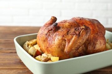 Delicious baked turkey and vegetables in baking dish on wooden table, closeup