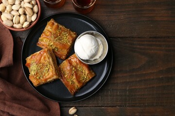Delicious baklava with crushed nuts and ice cream on wooden table, flat lay. Space for text