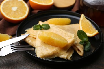 Delicious Crepes Suzette served on wooden table, closeup