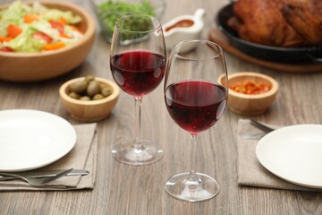 Red wine and delicious dinner served on wooden table