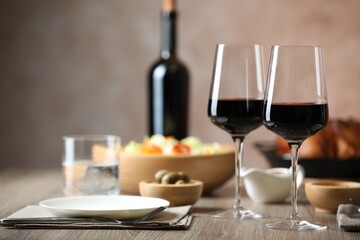 Red wine and delicious dinner served on wooden table, space for text