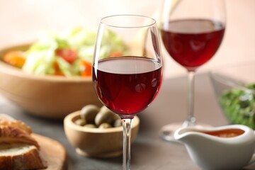 Red wine and delicious dinner served on table, closeup