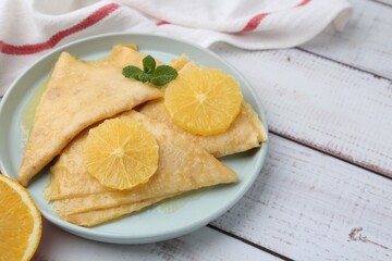 Delicious Crepes Suzette on white wooden table, closeup
