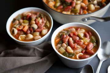 Bean,  Pasta and Vegetable Vegetarian Minestrone Soup in bowls and crock straight off the stove