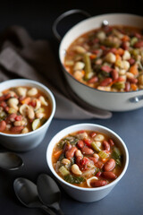 Bean,  Pasta and Vegetable Vegetarian Minestrone Soup in bowls and crock straight off the stove