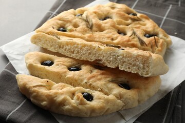 Slices of delicious focaccia bread with olives and rosemary on grey table, closeup