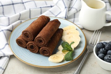 Delicious chocolate crepes with banana and blueberries served on light table, closeup