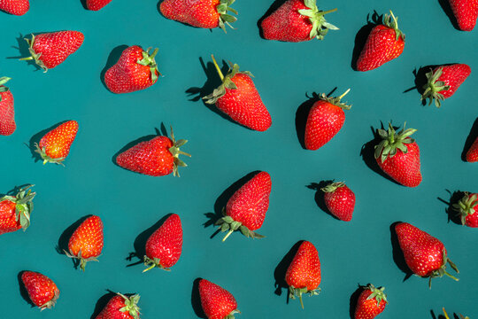 Fresh red strawberries on a turquoise colored table. 