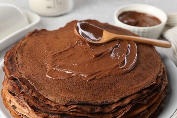 Delicious chocolate crepes with sweet paste on table, closeup
