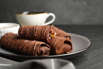 Delicious chocolate crepes with sweet paste and nuts on black table, closeup