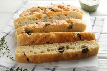 Slices of delicious focaccia bread with olives and thyme on table, closeup