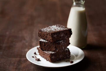 Stack of Black Bean Gluten Free Flourless  Brownies dusted with powdered sugar and plated with a glass of milk