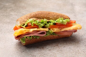 Delicious baguette sandwich with ham on grey table, closeup
