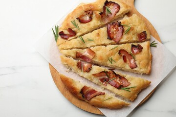 Slices of delicious focaccia bread with bacon and rosemary on white marble table, top view. Space for text