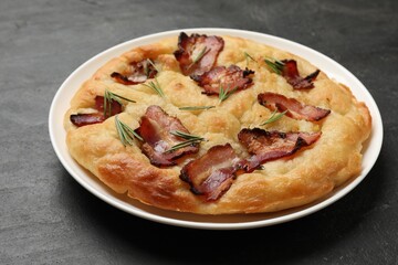 Delicious focaccia bread with bacon and rosemary on black table, closeup
