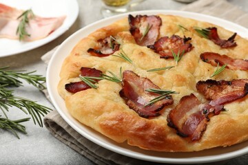 Delicious focaccia bread with bacon and rosemary on light grey table, closeup