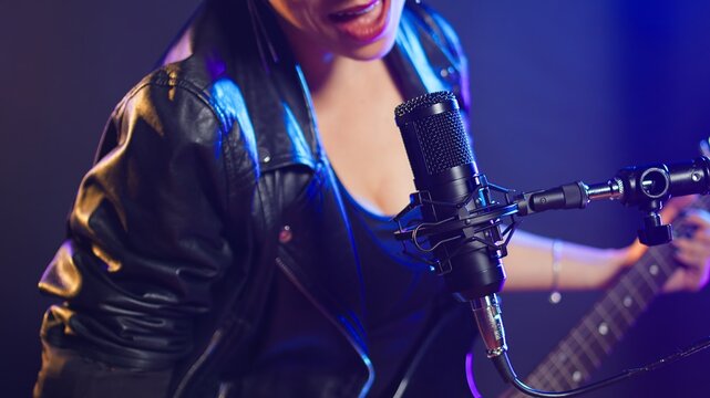 Pop star delivers a stunning live performance in a nightclub concert, powerful voice and trendy style captivating the audience. Bold edgy iconic vocal performance live. Close up. Camera A.