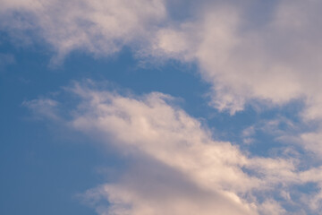 Obraz premium Soft fluffy clouds drift across a pale blue sky