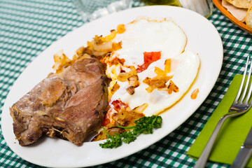 Close up of tasty cooked fried pork with fried eggs at plate