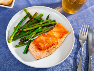 Tasty grilled salmon steak with asparagus garnish served on white plate
