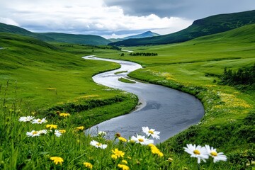 Obraz premium A winding river flowing through a green valley, with colorful wildflowers lining the banks