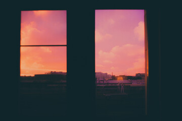 The view from the window with the city illuminated by the romantic pink sky at sunset creates an atmosphere of love and tenderness.