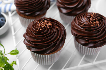 Tasty cupcakes with chocolate cream on white tiled table, closeup
