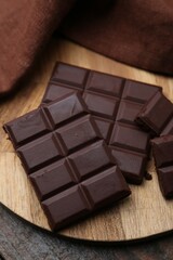 Pieces of delicious dark chocolate bar on wooden table, closeup