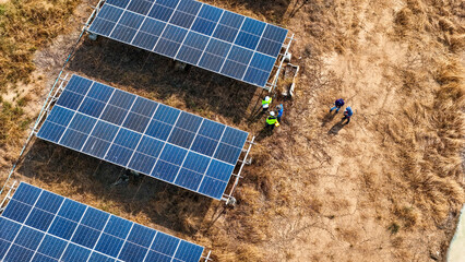 Renewable energy project featuring solar panels in a dry field, with technicians performing...