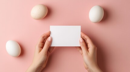 Obraz premium Woman's hands hold blank card surrounded by eggs on pink background.