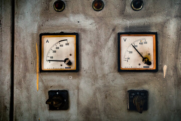 Analog ampere and voltage meter indicators with switches on old and rustic electrical control panel cabinet	