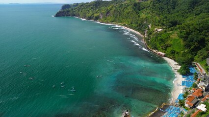 Aerial drone view of coastline with hills and trees, as well as view of coral cliffs and sea with waves from the ocean in Menganti Beach Kebumen Central Java Indonesia