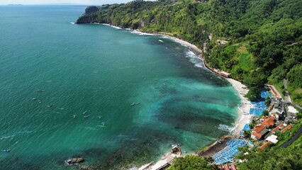 Aerial drone view of coastline with hills and trees, as well as view of coral cliffs and sea with waves from the ocean in Menganti Beach Kebumen Central Java Indonesia