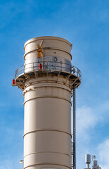 The top of an industrial cooling tower against a stark blue sky