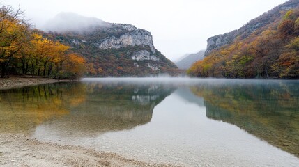 Serene lake surrounded by autumn foliage and misty mountains.