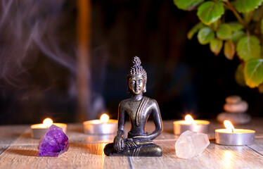 buda junto a un cuarzo blanco y una amatista, atrás velas encendidas y humo, esquina superior...