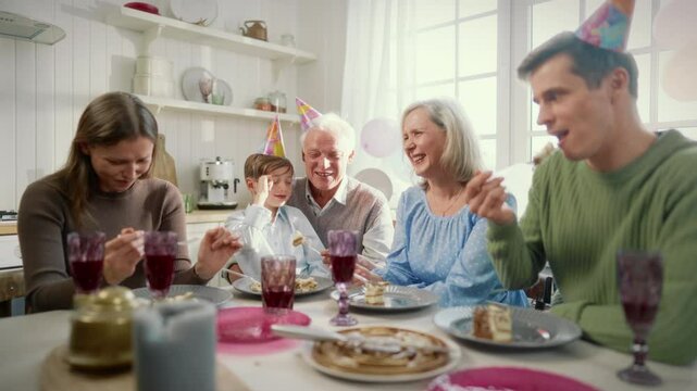 Little boy and his relatives celebrating anniversary and birthday at home. Portrait of happy family dinning together in weekend, three generations sitting together at table, past, present and future