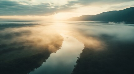 Serene sunrise over a winding river valley shrouded in morning mist.  A small boat navigates the calm water.