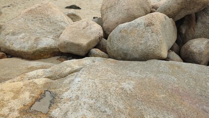 A group of large rocks scattered along a sandy beach at the Hon Chong Cape rock garden in Nha Trang City, Vietnam.