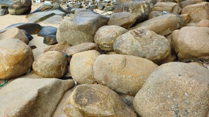 A group of large rocks scattered along a sandy beach at the Hon Chong Cape rock garden in Nha Trang City, Vietnam.