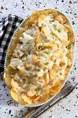 Platter of Blue Cheese Kettle Chips Baked with Alfredo Sauce and scallions with tongs