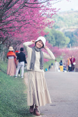 Happy travel Asian teen girl smile with sakura cherry blossoms tree on vacation while spring park nature background. , Journey trip lifestyle