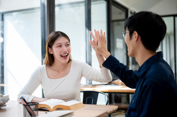 Fototapeta premium Two cheerful Asian students are giving each other a high five to celebrate their exam success.