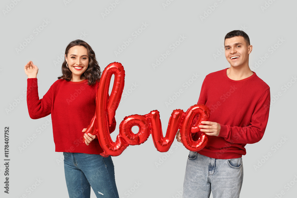 Canvas Prints Loving young couple with balloon in shape of word LOVE on grey background. Celebration of Saint Valentine's Day