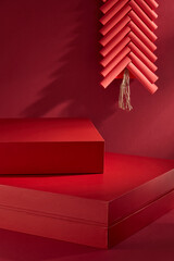 Obraz premium A promoting image with an Chinese New Year idea. A close-up view of red red rectangular podiums that are empty for placed products, decorated by red string of firecrackers, on a crimson background.
