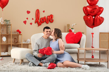 Young couple with heart-shaped air balloons and gift for Valentine's day at home