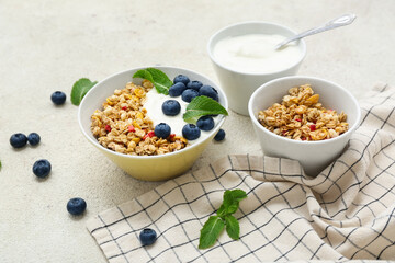 Bowls of tasty granola with yogurt on light grunge background