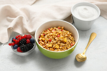 Napkin, bowls with tasty granola, yogurt and berries on pale blue background