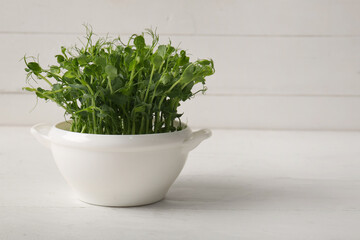 Bowl with fresh micro green on light wooden table