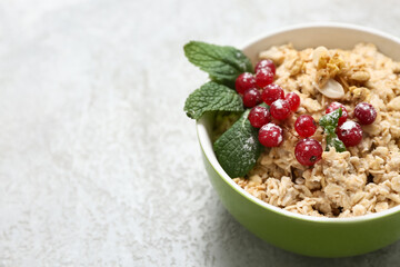 Bowl with tasty oatmeal and cranberries on grey grunge background, closeup